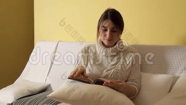 一个年轻的女孩穿着舒适温暖的毛衣在冬天的晚上在家，看书，睡觉